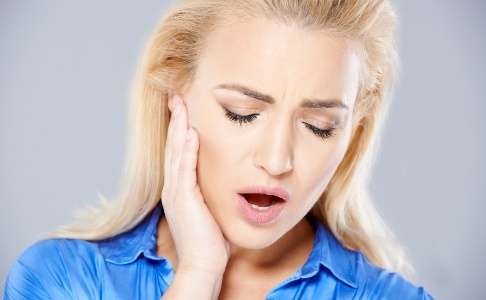 Woman in need of T M J therapy holding jaw in pain