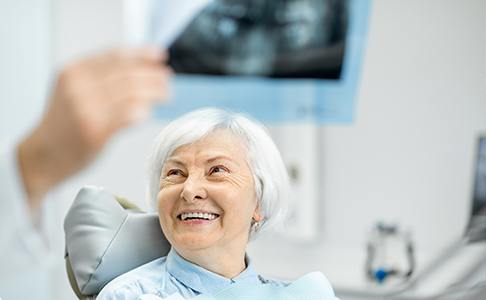 Woman in dental chair smiling at dentist