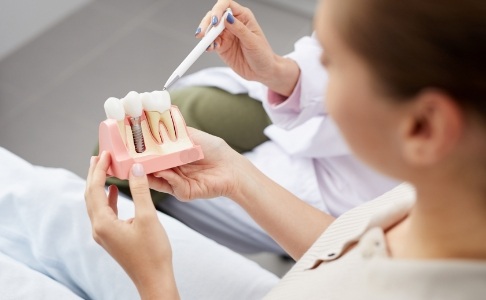 Dentist and patient looking at dental implant model