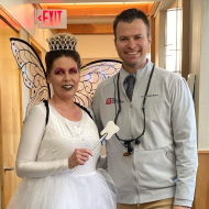 Dentist smiling with team member dressed as a tooth fairy