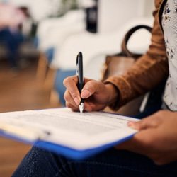 Closeup of patient filling out dental insurance paperwork in waiting room