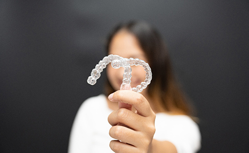 young woman holding two Invisalign clear aligners 
