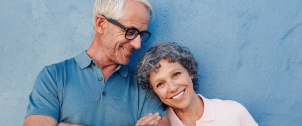 Man and woman smiling after replacing missing teeth