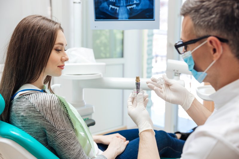 Dentist showing patient a dental implant