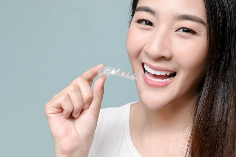 smiling person holding Invisalign tray