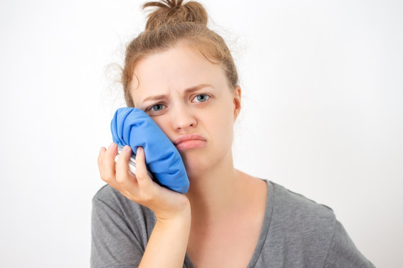 Young woman with a toothache holding an ice bag on her cheek